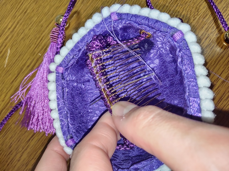 巻きつけた紐にコームを手縫いで固定する