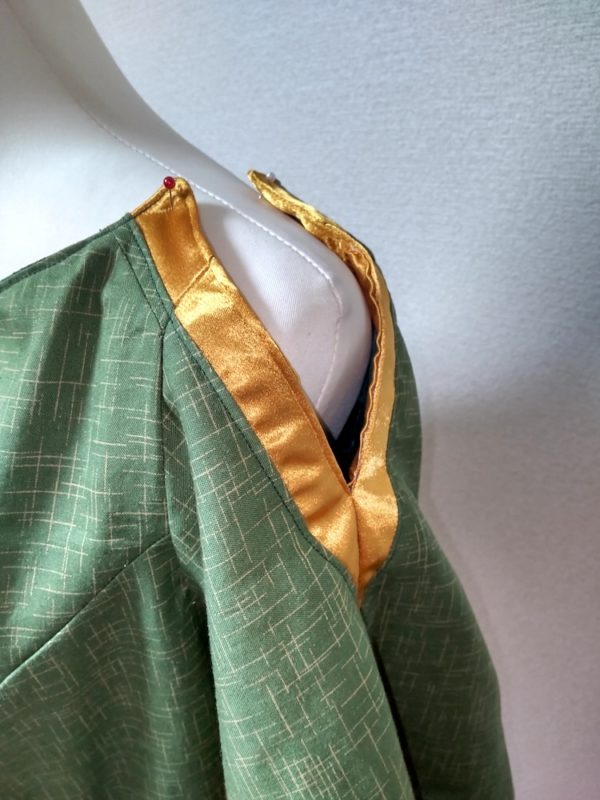 緑をベースにしたブラウスに形に金色のスリットが入った肩