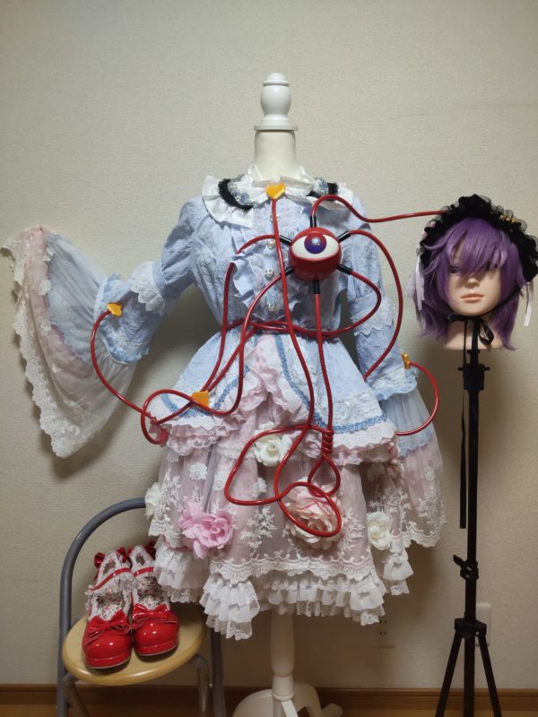 水色の丸襟のブラウスとピンク色の造花がついたスカート、紫色のウィッグ。 サードアイと赤い露リータ風の靴