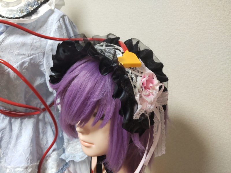 黒いフリルと薔薇の造花がついたヘッドドレスと紫色のウィッグ