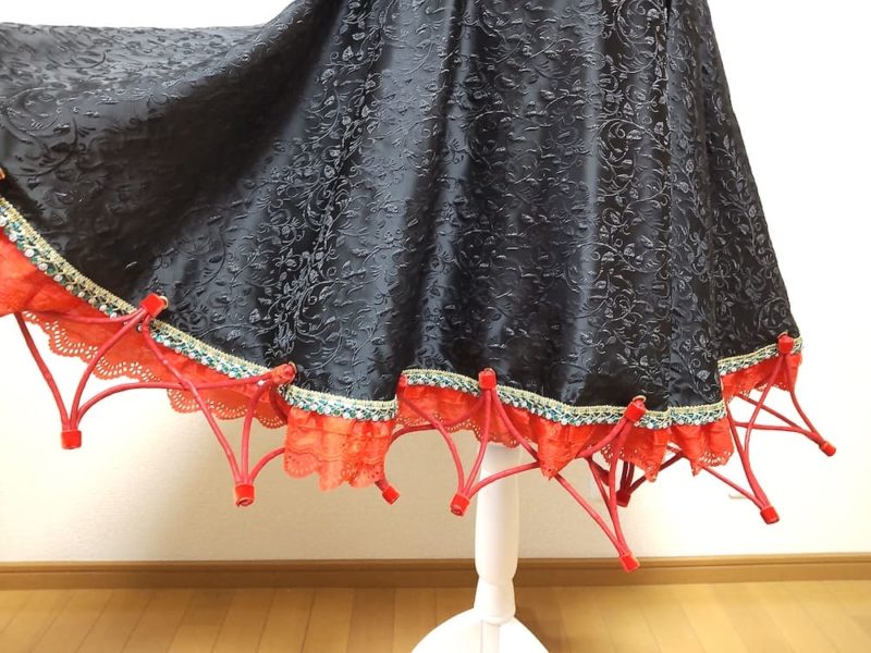 交差した赤い紐の裾と黒いスカート